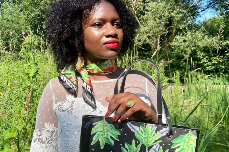 Young woman designer holding a striking bag, and wearing a scarf and ring of her own design
