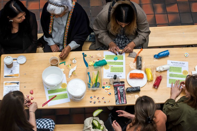 people arounda  table with coloured clay and tools for working it, making buttons and colourful craft objects