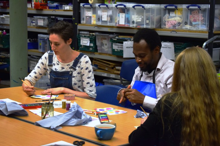 people round a table with craft materials working on a craft projects